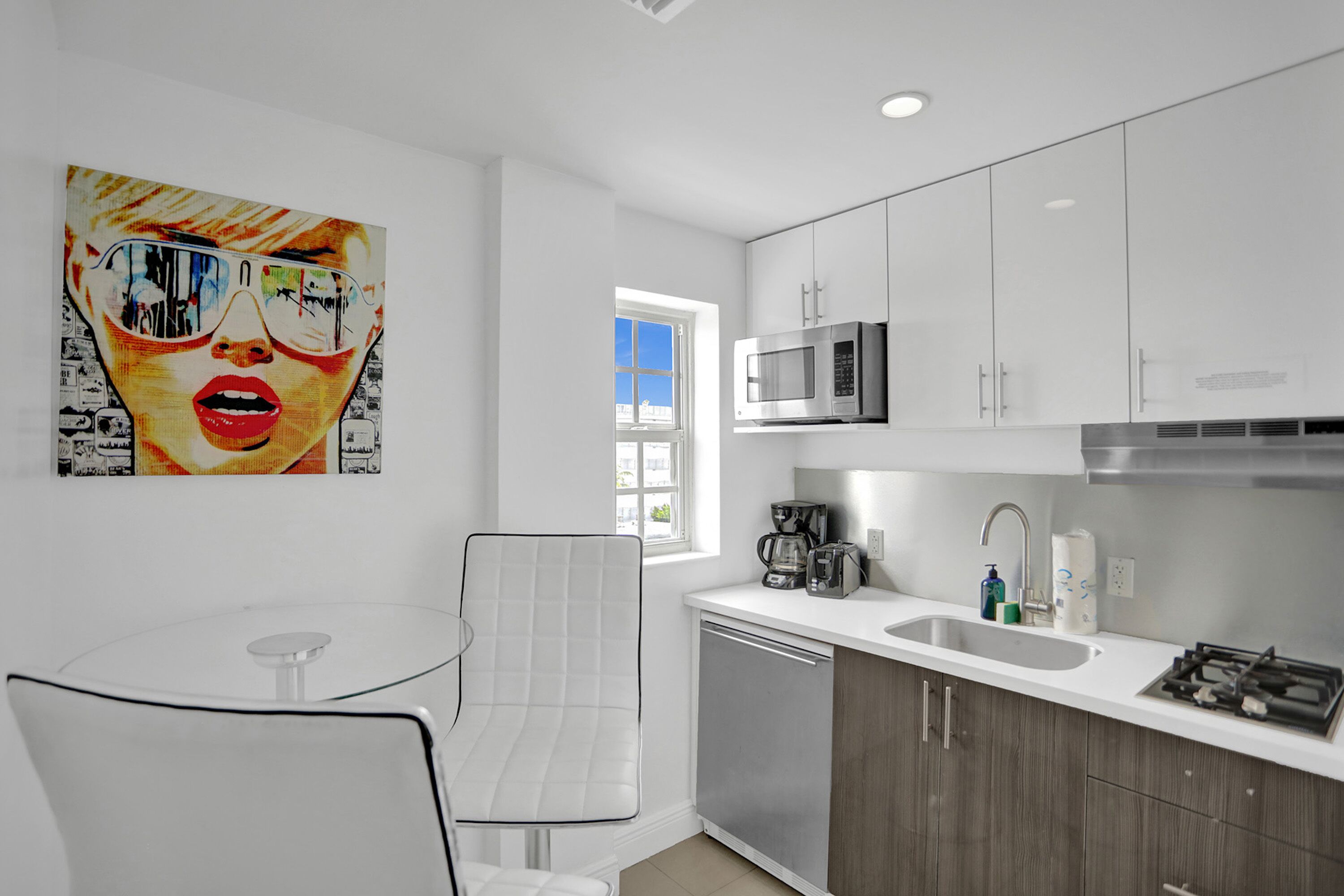 A modern kitchen with white cabinets, stainless steel appliances, and a glass table.