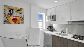 A modern kitchen with white cabinets, stainless steel appliances, and a glass table.