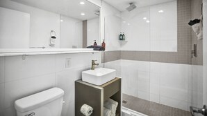 Ein modernes Badezimmer mit einem weißen Waschbecken, einer Toilette, einem Spiegel und einer Duschkabine.