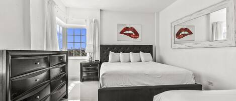 A modern bedroom with a large bed, a dresser, and two bedside tables.
