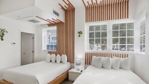 A modern bedroom with two beds, wooden headboards, a bedside table with a lamp, and a window with blinds. - NEW LISTING! Belleza Sobe Private Entrance studio Sleeps 4 (Miami)
