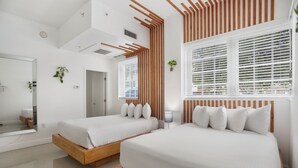 A modern bedroom with two beds, a large mirror, and a window with blinds. - NEW LISTING! Belleza Sobe Private Entrance studio Sleeps 4 (Miami)