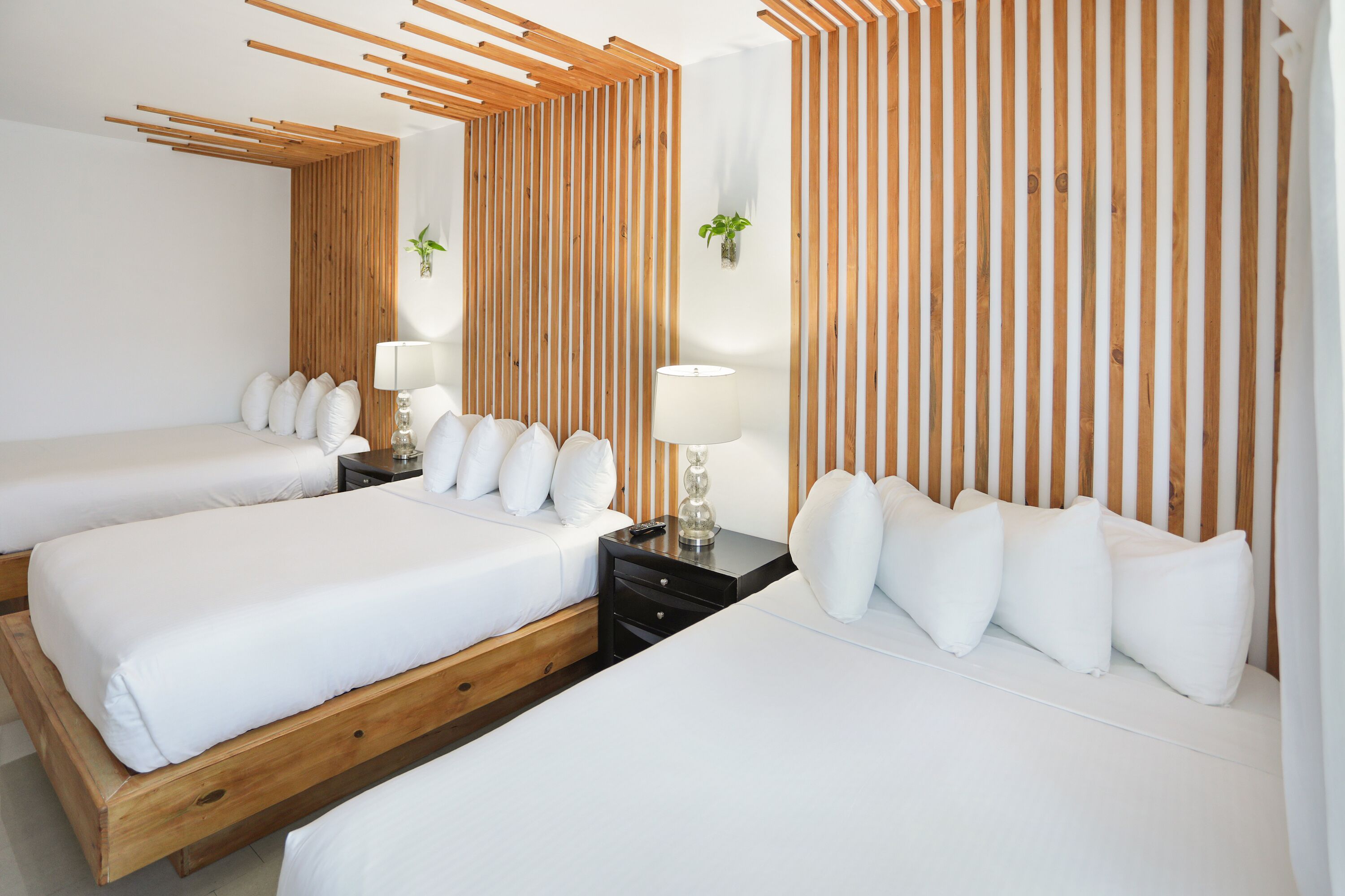 A hotel room with two beds, wooden slats on the walls, and a small table with a lamp.