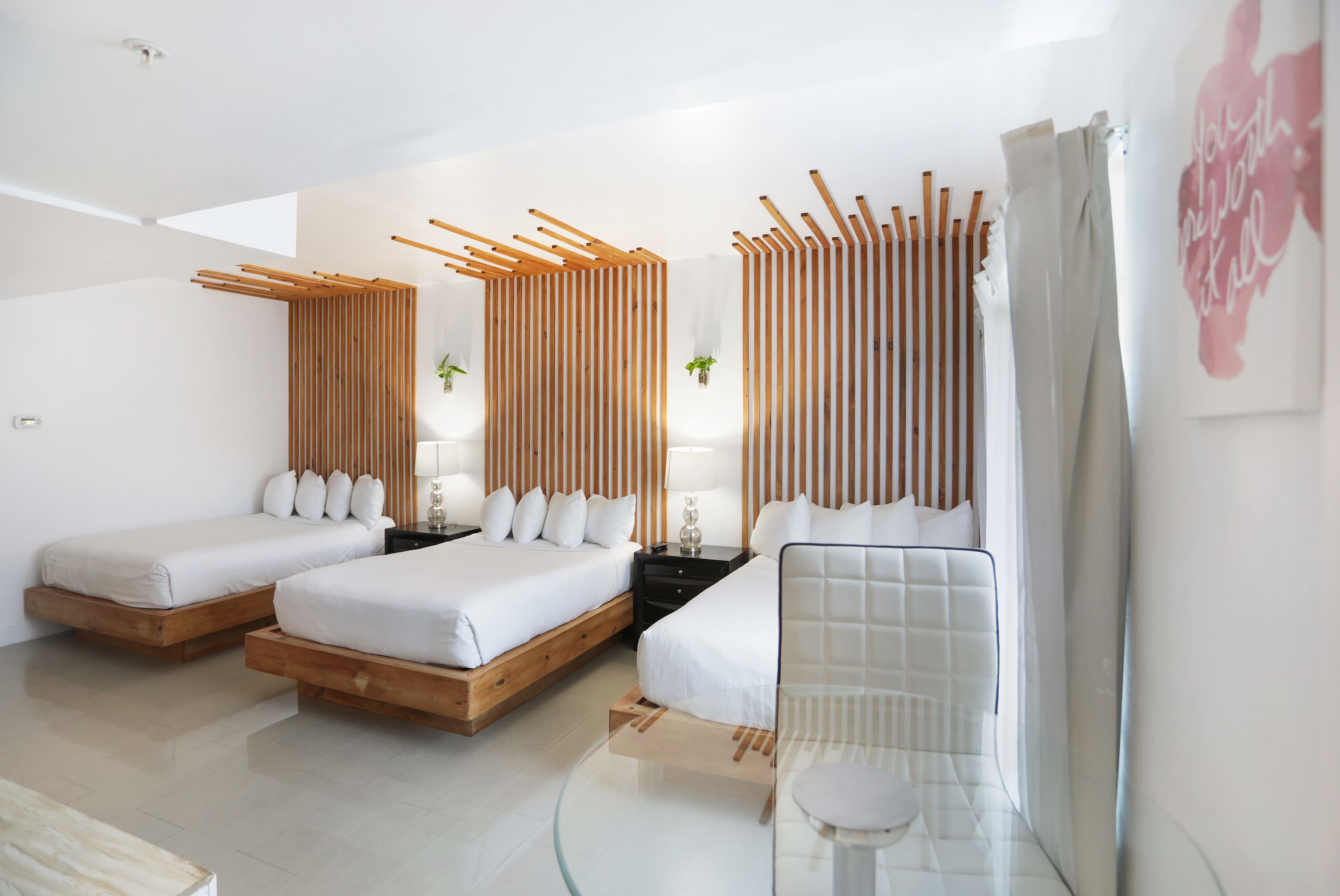 Ein modernes Hotelzimmer mit zwei Betten, einem Glastisch und einer Holzwand.