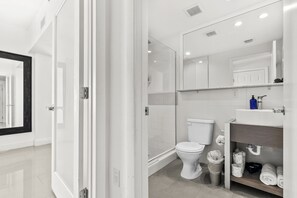 Un baño moderno con cabina de ducha de vidrio, inodoro blanco y tocador con espejo.
