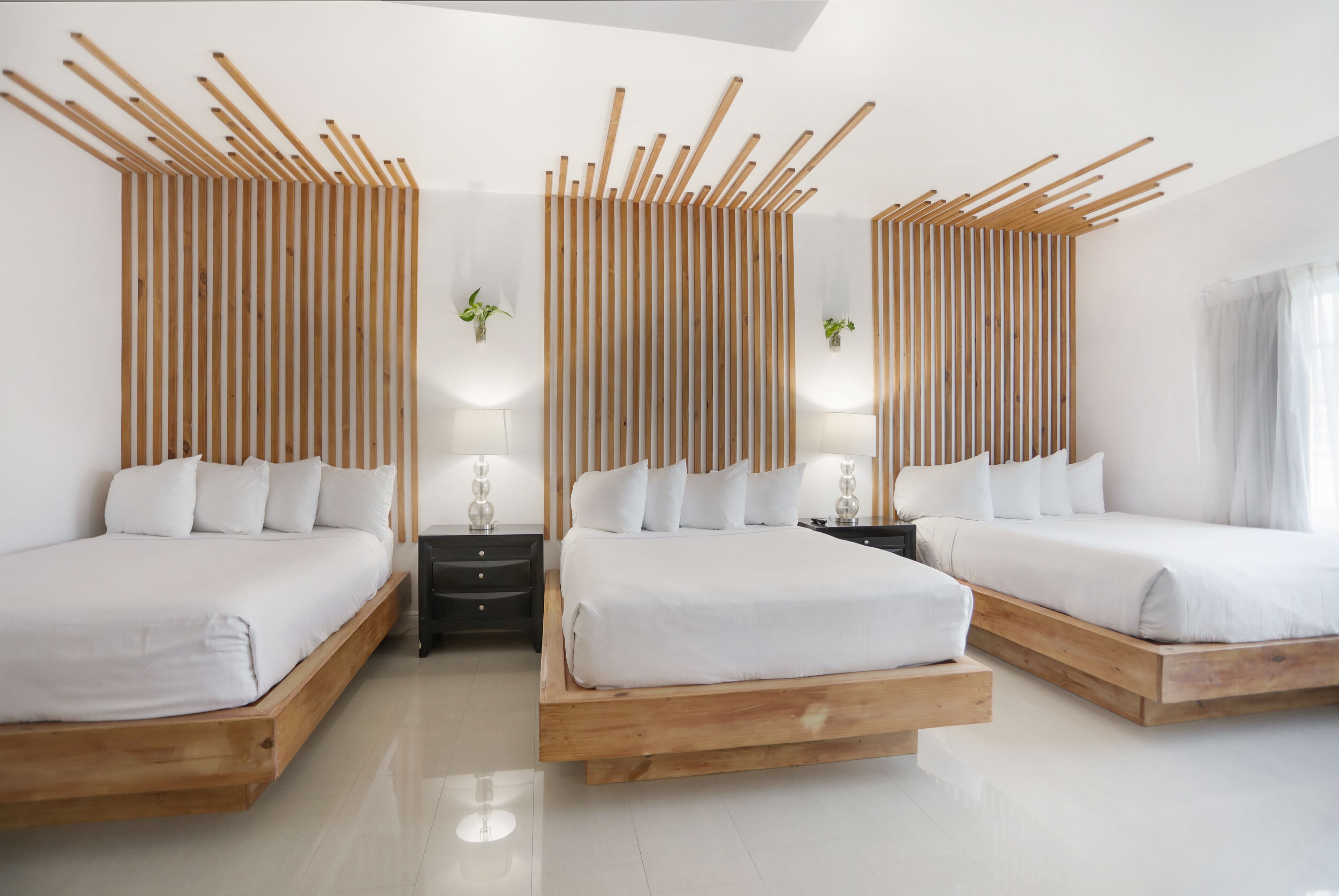 Een moderne slaapkamer met twee bedden, houten hoofdborden, nachtkastjes en wandlampen.