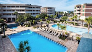 Um hotel com várias piscinas, palmeiras e um céu azul límpido.