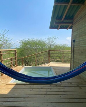 A wooden deck with a glass-enclosed hot tub and a hammock. - Ankua Eco Hotel  (Usiacurí)