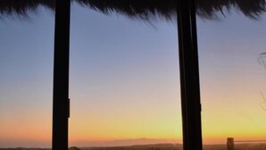 Una habitación con un ventanal grande que da a un paisaje durante el atardecer.