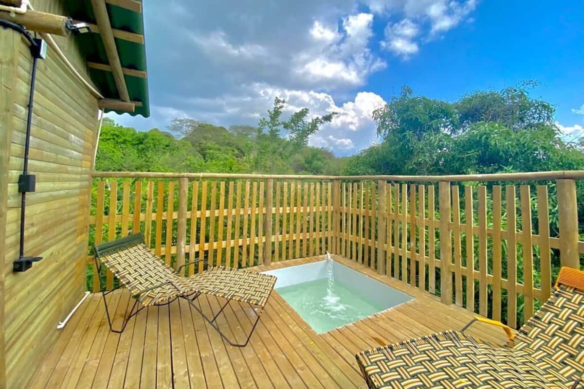 A wooden deck with a hot tub, lounge chairs, and a wooden fence.