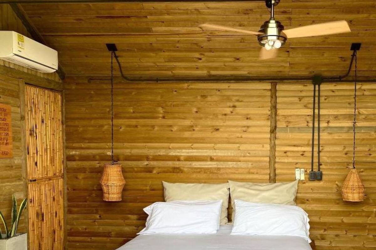 A bedroom with a wooden bed, a ceiling fan, and two hanging lamps.