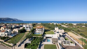 A coastal residential area with modern houses, a swimming pool, and a clear view of the sea. - Luxurious villa with a large pool, 750m from the beach. (Asprouliani)