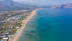 An aerial view of a coastal area with a beach, buildings, and mountains. - Luxurious villa with a large pool, 750m from the beach. (Asprouliani)