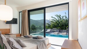A modern bedroom with a large sliding glass door leading to a pool area. - Luxurious villa with a large pool, 750m from the beach. (Asprouliani)