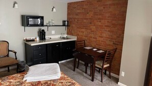 A compact room with a kitchenette, a dining area, and a bed. - Double Queen Guestroom (Corning)