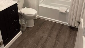 A modern bathroom with a toilet, sink, and shower. - Double Queen Guestroom (Corning)