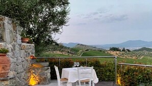 An outdoor dining area with a stone wall, a wooden deck, and a table set for two with white tablecloths and chairs. - Room in B&B - Room Overlooking the Vineyards and Florence (Carmignano)