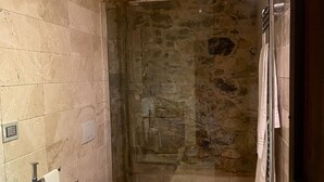 A bathroom with a stone wall, a glass sink, a toilet, and a shower area. - Room in B&B - Room Overlooking the Vineyards and Florence (Carmignano)