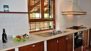 A kitchen with a double sink, a stove, and wooden cabinets. - Villa Il Casolare Country House With Pool on Sperlonga's Hill (Itri)
