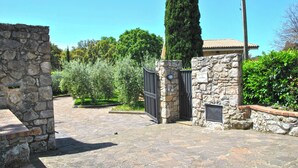 A stone pathway leading to a gated entrance with a stone wall and a tall tree. - Villa Il Casolare Country House With Pool on Sperlonga's Hill (Itri)