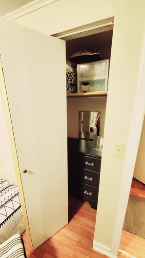 A narrow hallway with a door on the left, a wooden floor, and a black cabinet with drawers. - Room-black-white Rm By Yale U (New Haven)