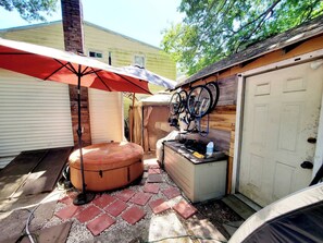 A backyard with a patio area, a hot tub, a covered seating area, and bicycles mounted on the wall. - Room-black-white Rm By Yale U (New Haven)