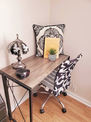 A wooden desk with a lamp, a chair, a small potted plant, a pillow, and a framed menu. - Room-black-white Rm By Yale U (New Haven)