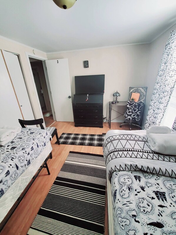 A bedroom with two beds, a dresser, a television, and a patterned rug. - Room-black-white Rm By Yale U (New Haven)