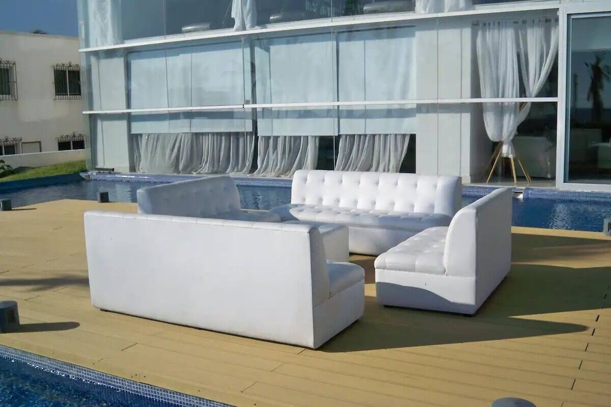 A poolside area with a white sofa and a white armchair.