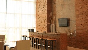 Un interior modern amb una paret d'accent de fusta, una zona de bar amb tamborets i un televisor de pantalla plana fixat a la paret.