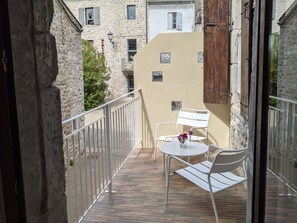 Ein Balkon mit weißem Metallgeländer, einem kleinen runden Tisch und zwei weißen Stühlen.