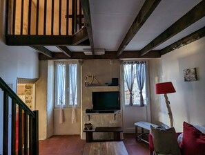 Ein Wohnzimmer mit Fernseher, Holzbalken, einer Steinwand und einer roten Lampe.