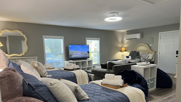 A well-lit hotel room with two beds, a television, a desk, and a comfortable seating area. - 4 Bedroom Retreat Sleeps 11 with Dock on Lake Weir near The Villages & Orlando (Summerfield)