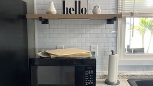 A kitchen with a microwave, a wooden cutting board, a 'hello' sign, and a window with blinds. - 4 Bedroom Retreat Sleeps 11 with Dock on Lake Weir near The Villages & Orlando (Summerfield)