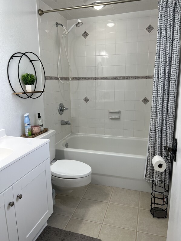 A bathroom with a toilet, bathtub, shower, and a sink with a mirror and shelf. - 4 Bedroom Retreat Sleeps 11 with Dock on Lake Weir near The Villages & Orlando (Summerfield)