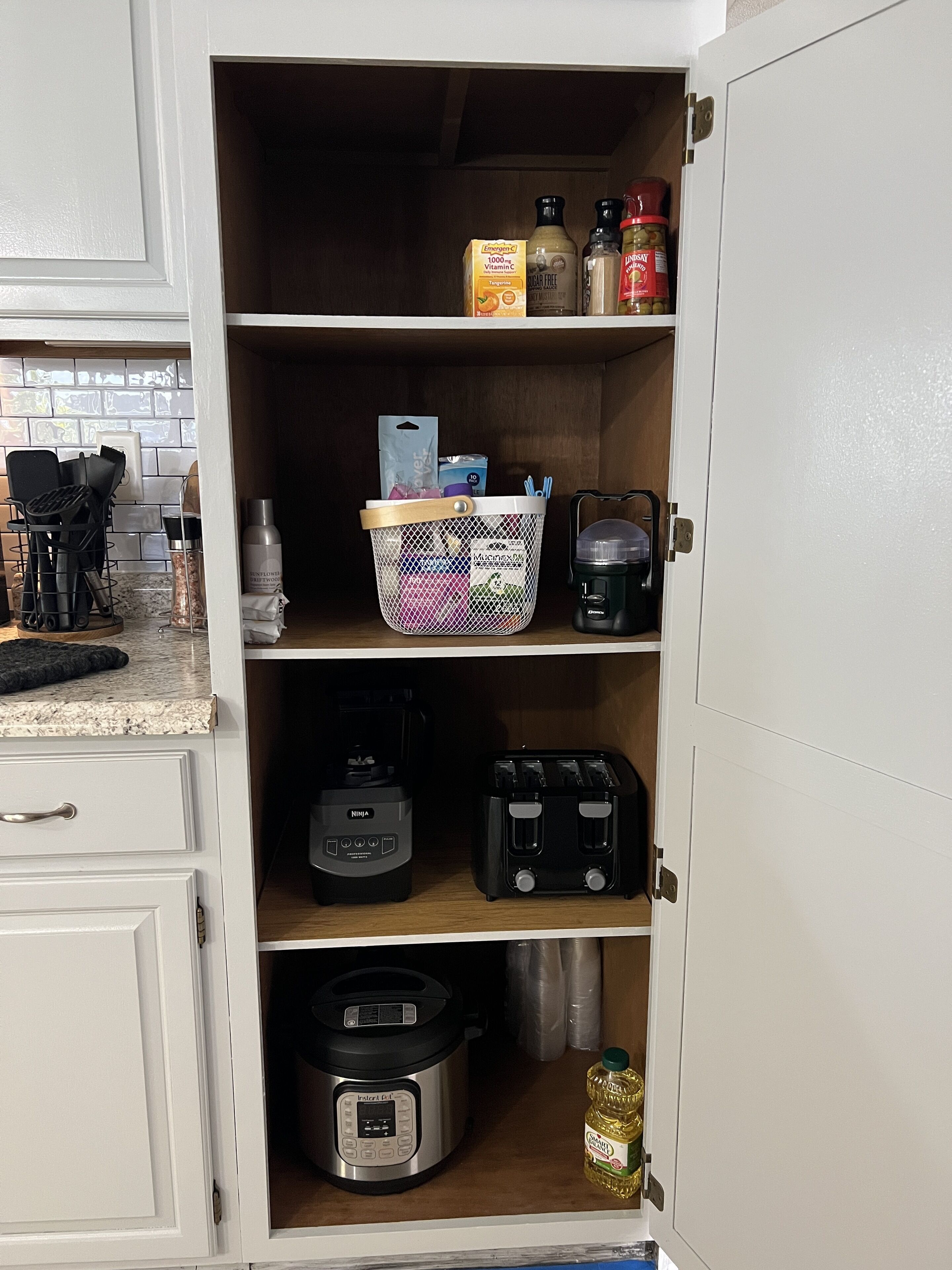 Una despensa de cocina con estantes que contienen diversos alimentos, una cafetera, un tostador y una olla a presión Instant Pot.