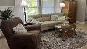 A living room with a brown sofa, a beige sofa, a wicker coffee table, and a patterned rug. - 4 Bedroom Retreat Sleeps 11 with Dock on Lake Weir near The Villages & Orlando (Summerfield)