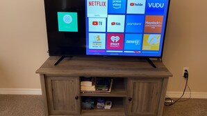 Un televisor de pantalla plana sobre un mueble de madera con un estante inferior.