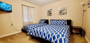 Un dormitorio con una cama, un televisor montado en la pared y dos obras de arte en las paredes.