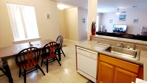 Una cocina con una mesa de comedor, sillas, lavavajillas y un lavamanos.