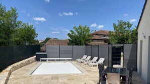 Un espacio al aire libre cubierto con mesa de billar, sillas de descanso y mesa de comedor con sillas.