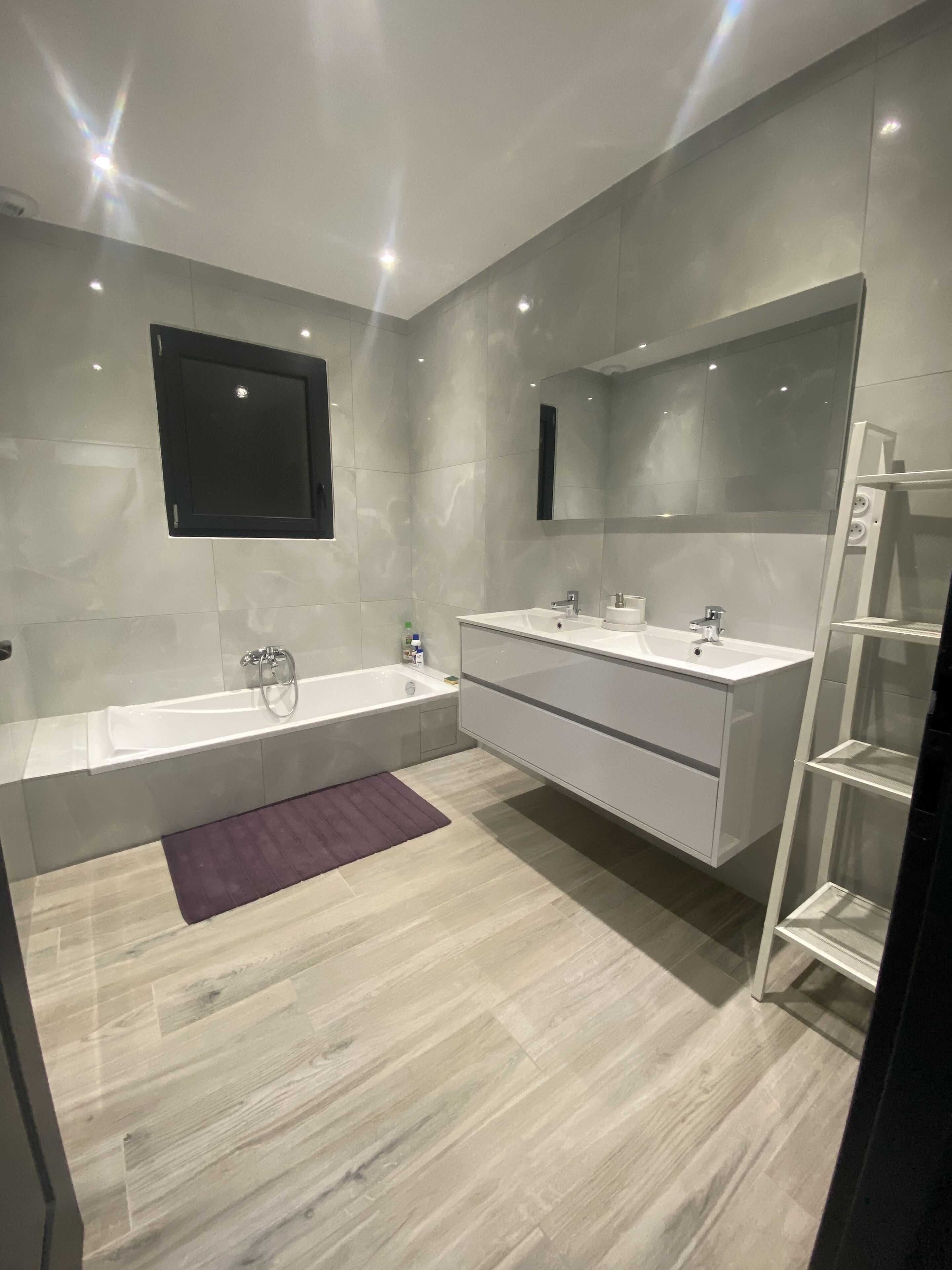 A modern bathroom with a bathtub, a large mirror, and a vanity with a sink.