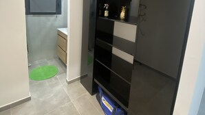 Habitación compacta con armario empotrado, tocador pequeño y un tapete verde en el suelo.