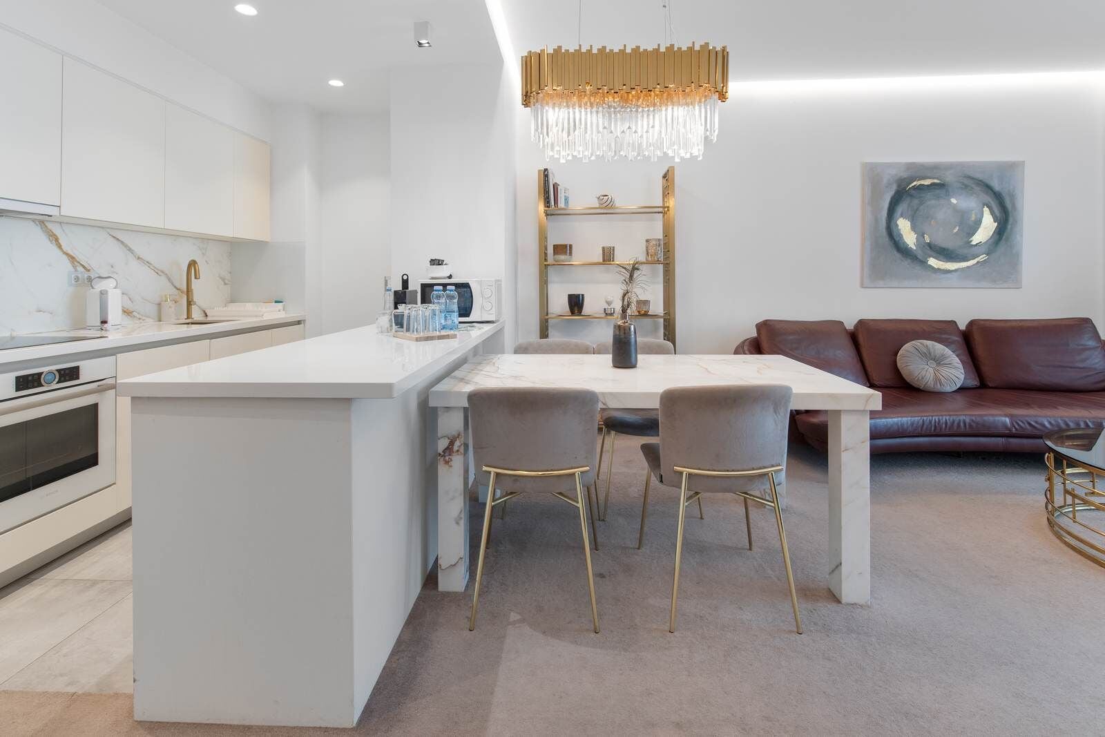 Una cucina moderna con mobili bianchi, un'isola centrale e un'area pranzo con tavolo e sedie.