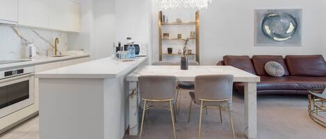 Una cucina moderna con mobili bianchi, un'isola centrale e un'area pranzo con tavolo e sedie.