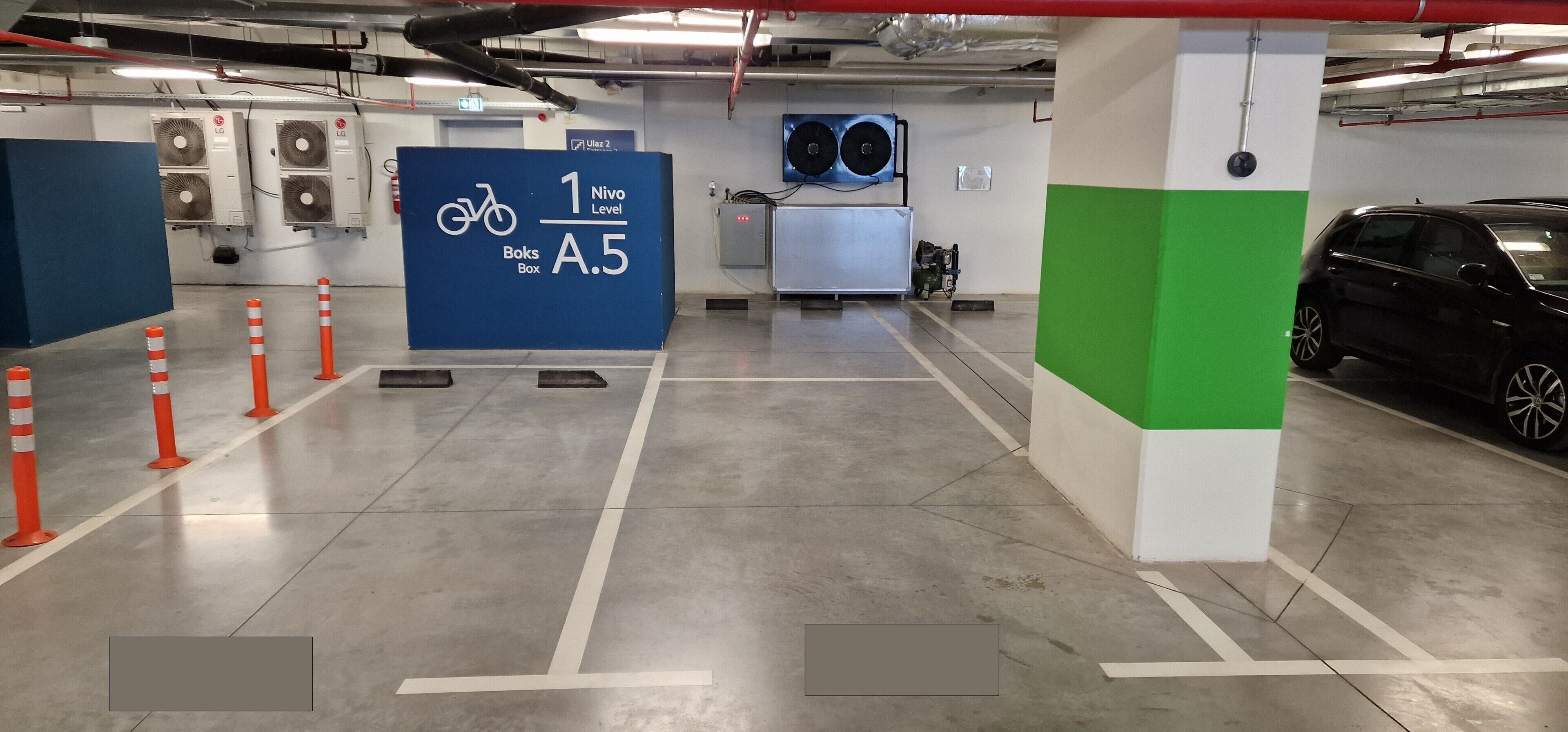 A parking garage with marked bicycle parking, air conditioning units, and a car parked to the right.