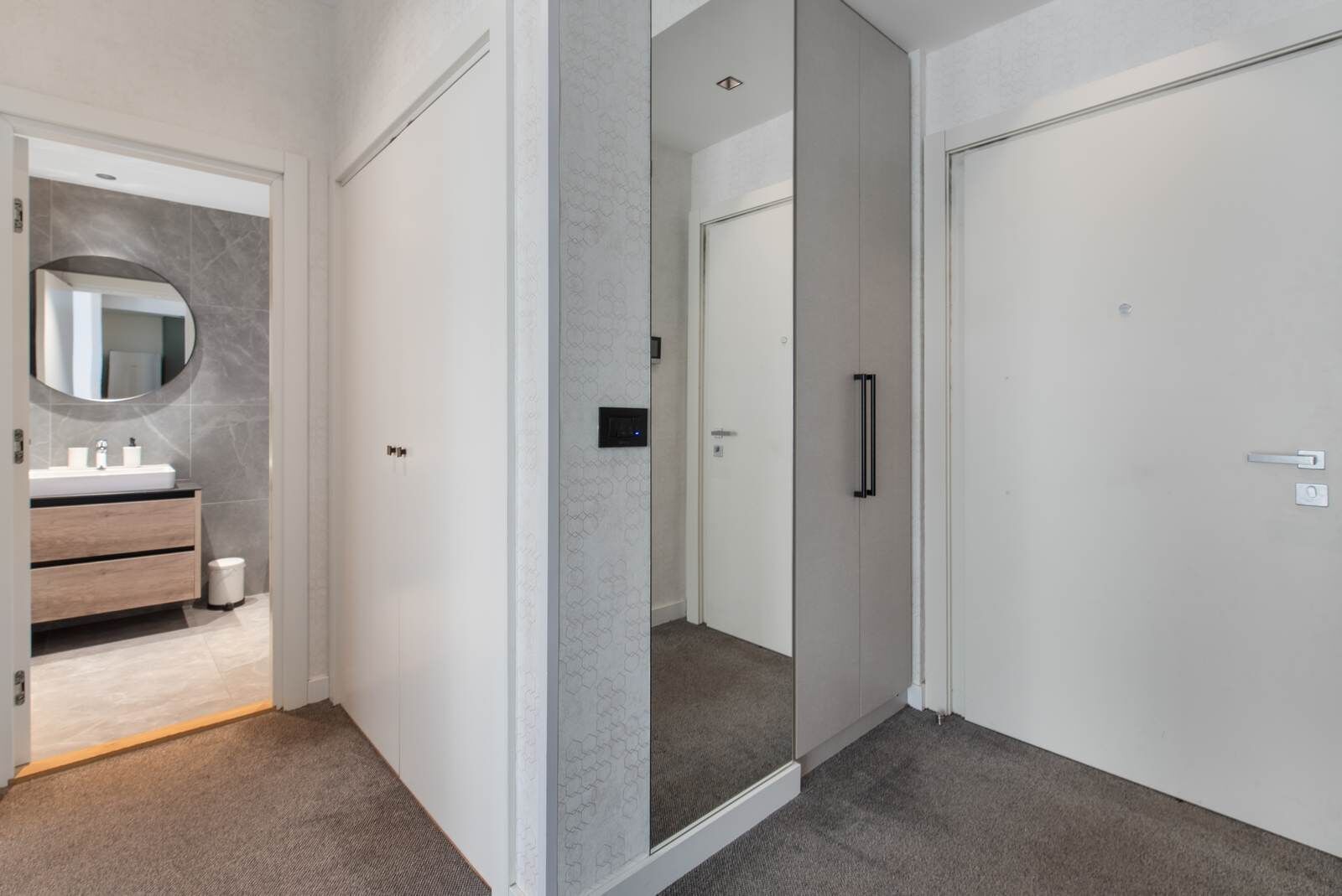 A modern bathroom with a vanity, mirror, and a toilet.