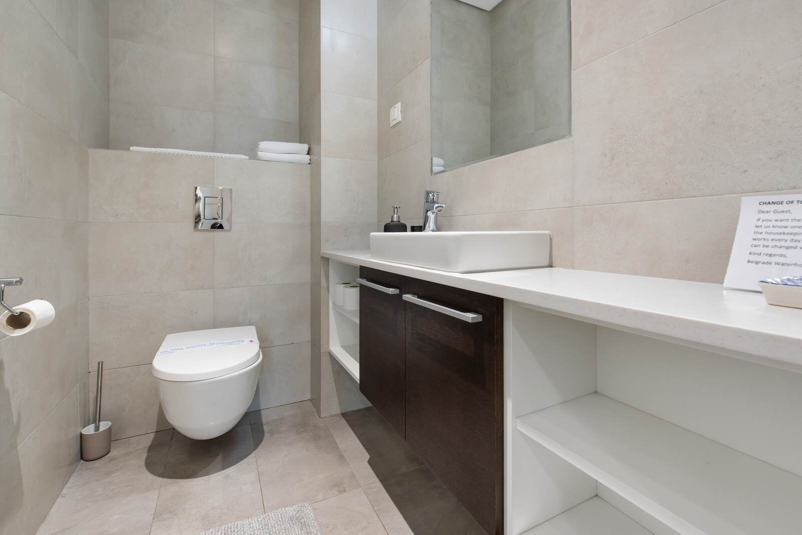 Un baño moderno con inodoro, lavamanos y espejo.