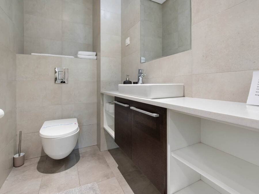 Un baño moderno con inodoro, lavamanos y espejo.