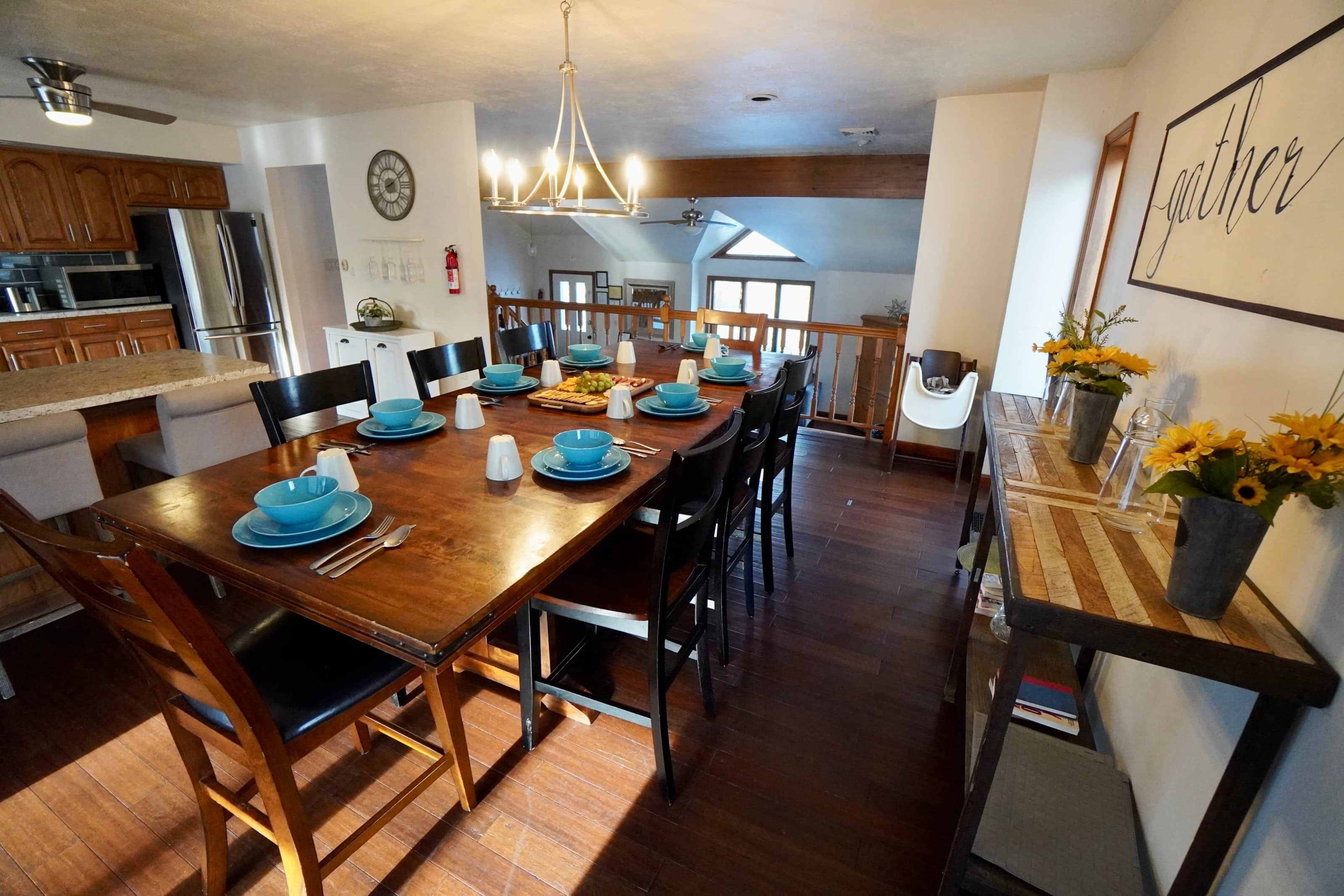 A spacious dining area with a long wooden table set for six, surrounded by chairs.